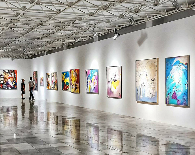 Art gallery with concrete floors, white walls, and large framed artwork.
