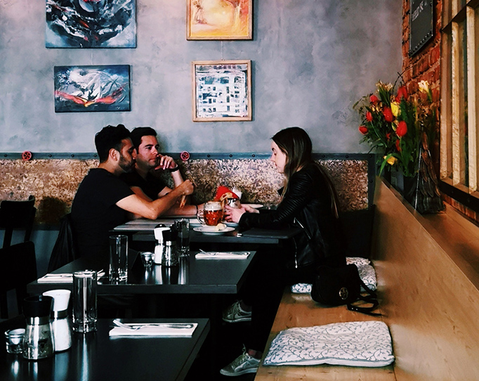 Three people seated at table in restaurant with wall art and decor.